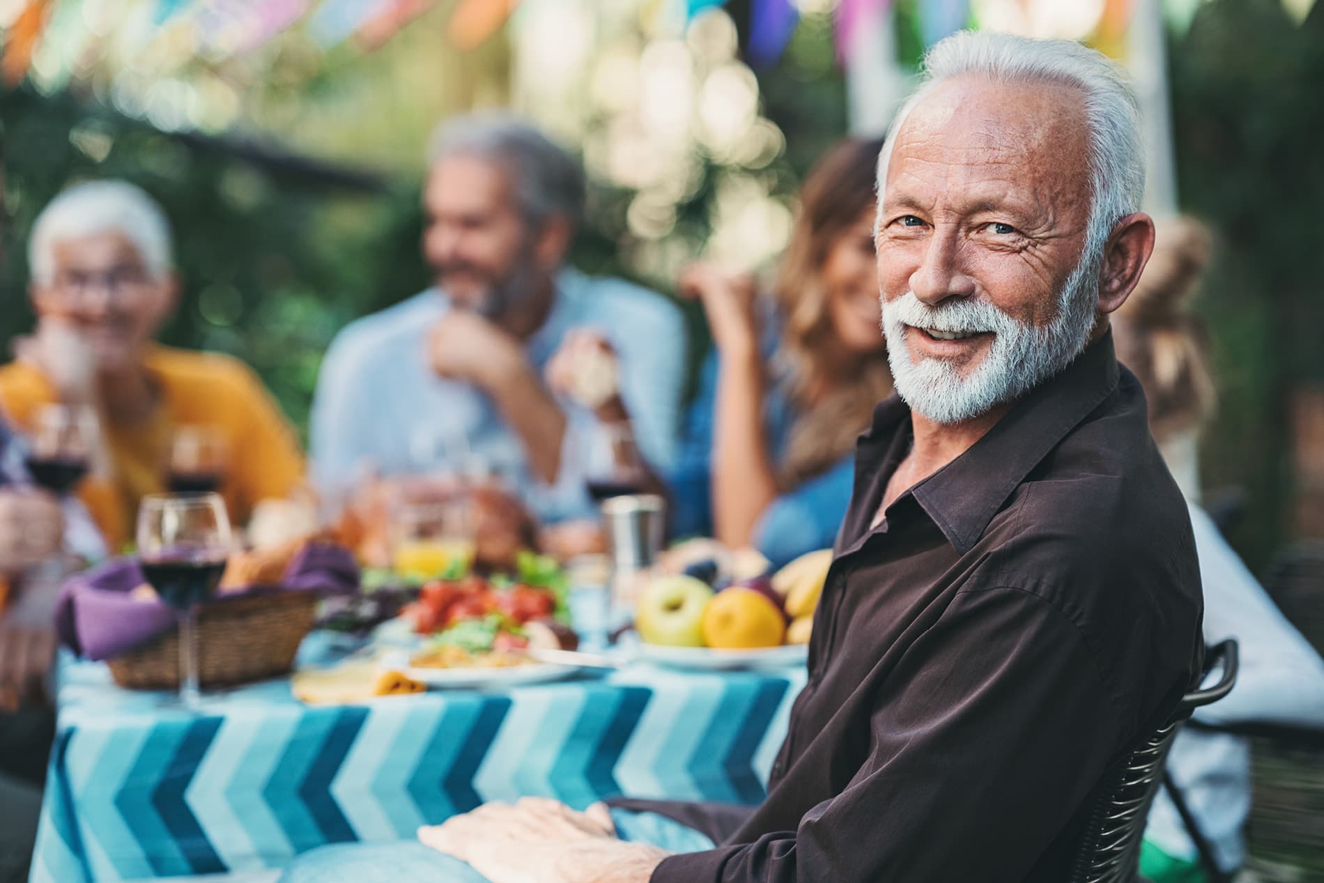 elderly man smiling at a dinner with friends