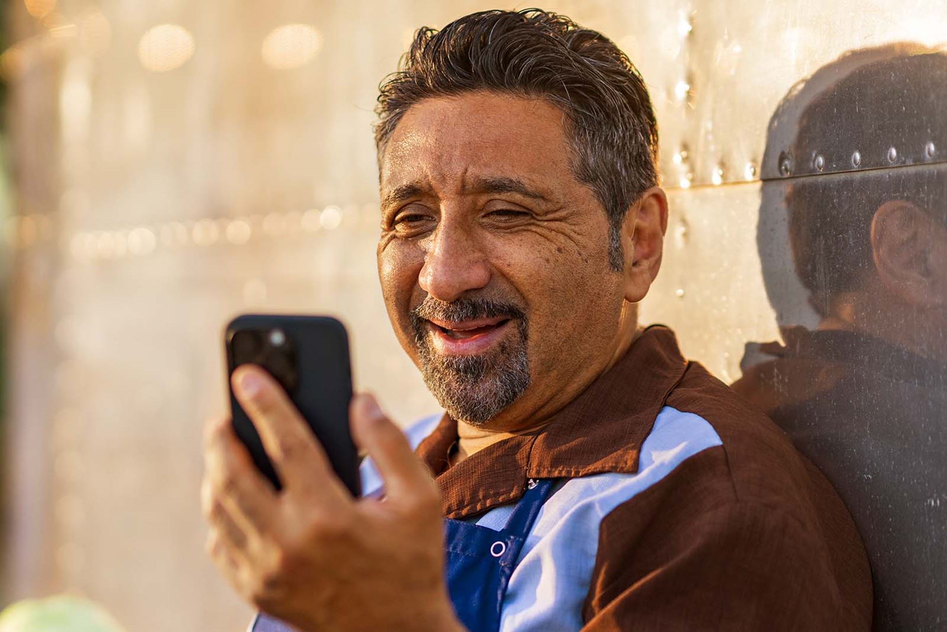 man wearing Rexton Reach R-Li smiling and speaking into his smartphone